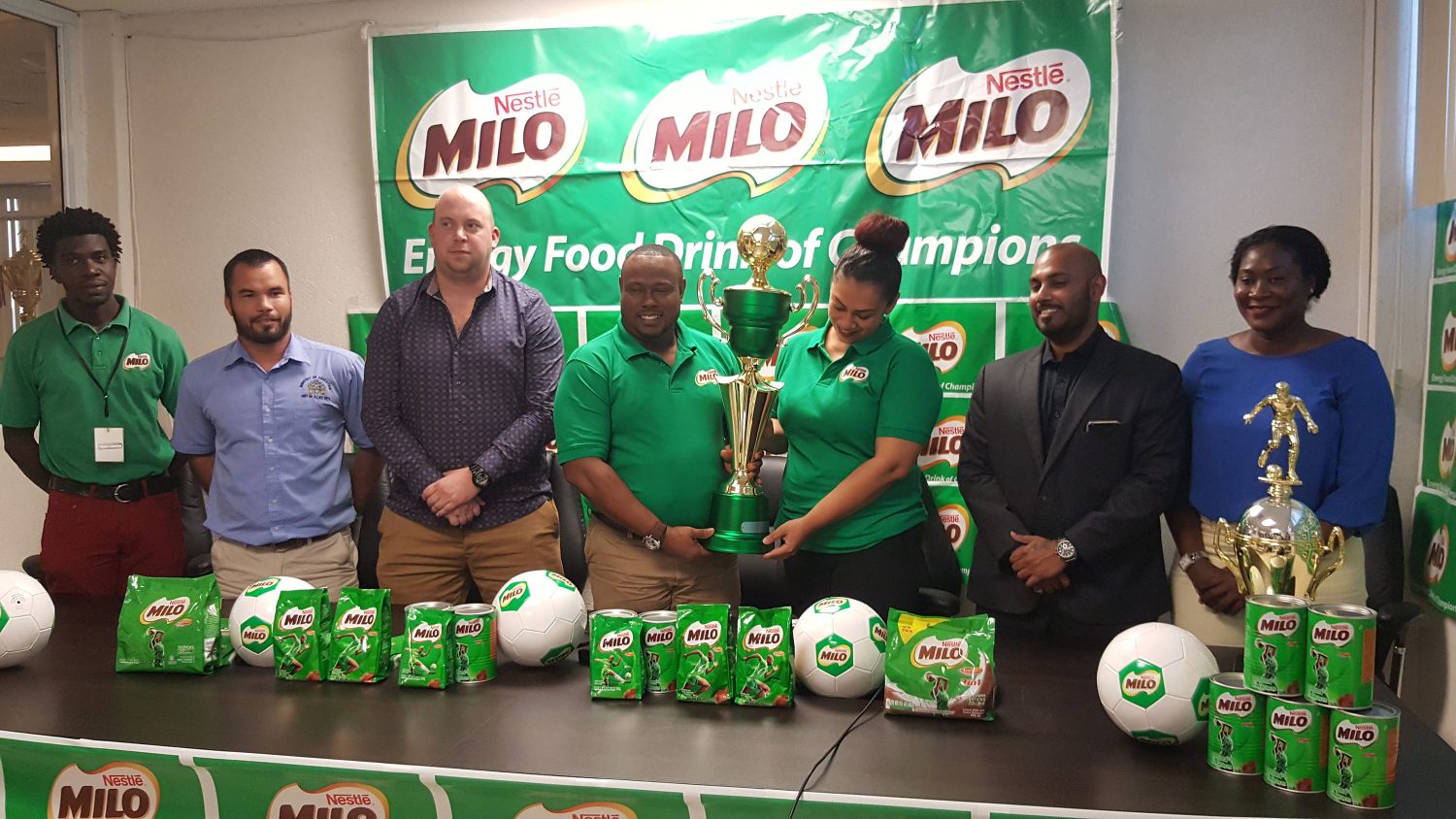 Co-Director of the Petra Organization Troy Mendonca (centre) collecting the championship trophy from Brand Manager Christel Van Sluytman following the official launch of the 6th Milo U18 Secondary Schools Football Tournament. Among the members of the launch party are Petra Representative Mark Alleyne (left), Ministry of Education Allied Arts Department representative Nicholas Fraser (2nd from left), GFF Technical Director Ian Greenwood (3rd from left) and Director and Executive Officer of M. Beepats and Sons Jonathan Beepat (2nd from right)