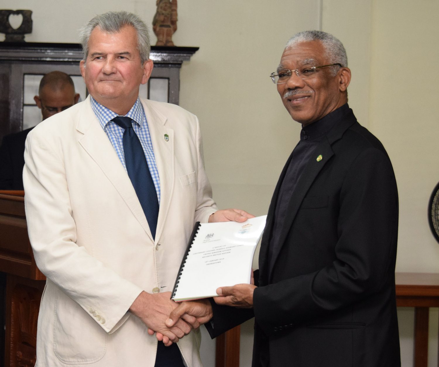 Russell Combe (left) handing over the report to President David Granger (Ministry of the Presidency photo)