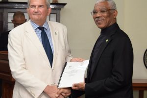Russell Combe (left) handing over the report to President David Granger (Ministry of the Presidency photo)