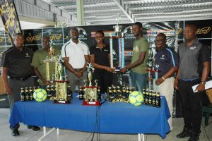 Tournament Co-Coordinator Travis Bess, collecting the championship trophy from Colours Representative Creanna Damon, while other members of the launch party share the moment. Also in the picture from left to right are Outdoor Events Manager Mortimer Stewart, Co-Coordinator Errol Beard, Guinness Brand Manager Lee Baptiste, Communications Director Troy Peters and Referees Coordinator Wayne Griffith
