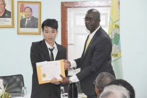 Best Graduating Land Surveyor,  Katfai Sue (left)  receives his Certificate of Completion from Trevor Benn, Chief Executive Officer of the Guyana Lands and Surveys Commission  (Ministry of the Presidency photo)