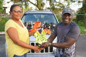 Caption Secretary of the GRFU, Petal Adams receiving the quantity of footwear on Friday at the National Park from Sheldon Murray on behalf of USA based Sheldon White.