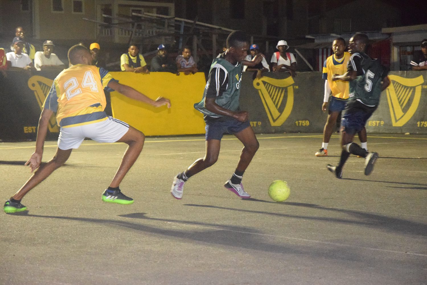 Dorville Stewart (centre) of Dream Team, attempting to evade the challenge of Nick Nestor (24) of ESPN, during their semi-final clash in the Guinness ‘Greatest of the Streets’ West Demerara/East Bank Demerara Zone, at the Pouderoyen tarmac
