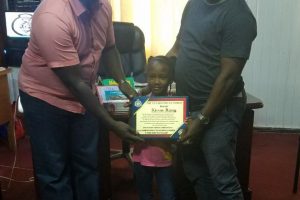 Seven-year-old Kissan Henry receiving a plaque from Crime Chief Paul Williams (at left) and Deputy Crime Chief Supertindent Michael Kingston.  