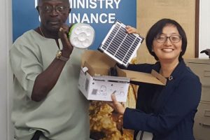 Permanent Secretary of the Ministry of Education Vibert Welch receiving a solar lantern from UN Resident Coordinator Mikiko Tanaka, who was representing Panasonic Inc.