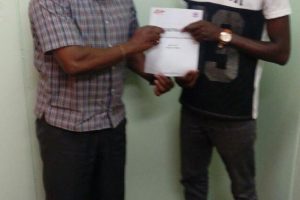 Colin Lewis (right) displays his travel insurance in the presence of President of the GBA, Steve Ninvalle before departing yesterday for Mexico. Lewis and Keevin Allicock departed yesterday for a one-week training camp in Mexico City, Mexico which will be followed by their participation in the CAC Qualifiers in Tijuana from March 10-18th.