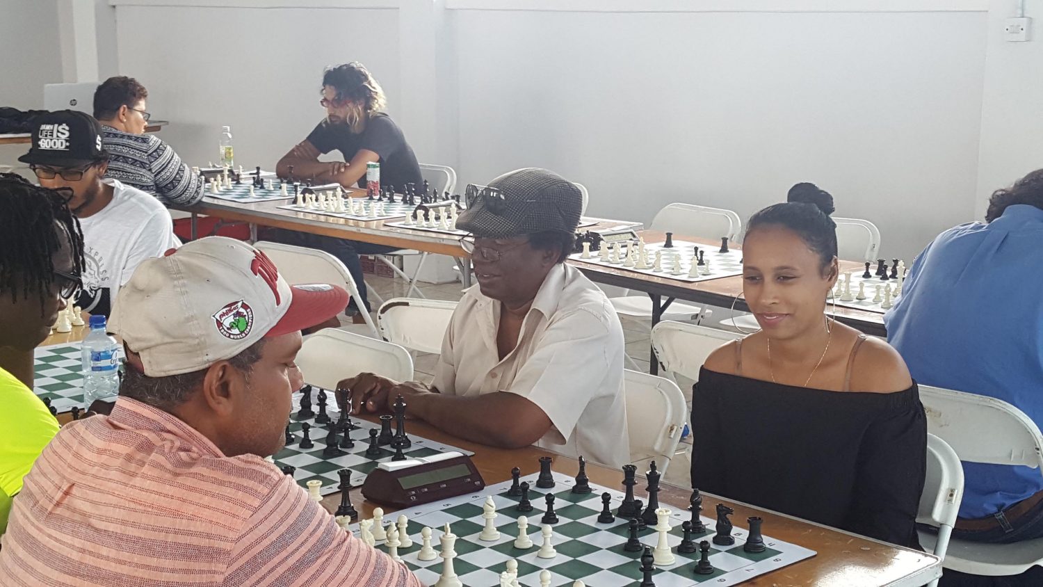 During the recent National Senior Qualifier Chess Tournament at the Aquatic Centre, Liliendaal, a number
of casual games were played as lunches were served. Stephanie Chung (right), a student of chess and onlooker at the qualifier, faces Rose Hall’s Kriskal Persaud during a fun game. Next to Chung is former national chess player David Khan. Rashad Hussain is in concentration against Maria Varona-Thomas in the background. 