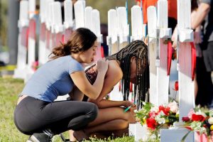 A senior at Marjory Stoneman Douglas High School weeps in front of a cross and Star of David for shooting victim Meadow Pollack while a fellow classmate consoles her at a memorial by the school in Parkland, Florida, U.S. February 18, 2018. REUTERS/Jonathan Drake