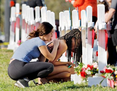 A senior at Marjory Stoneman Douglas High School weeps in front of a cross and Star of David for shooting victim Meadow Pollack while a fellow classmate consoles her at a memorial by the school in Parkland, Florida, U.S. February 18, 2018. REUTERS/Jonathan Drake