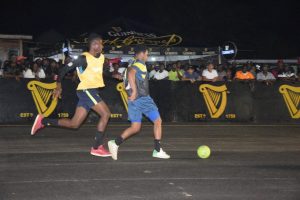 Dellon John (left) of Dream Team in hot pursuit of a Harmony Warriors player, at the Pouderoyen Tarmac in the in the Guinness ‘Greatest of the Streets’ West Demerara/East Bank Demerara Zone