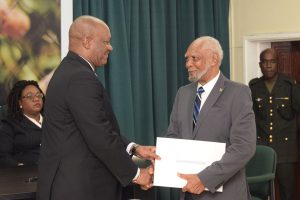 Retired Justice Donald Trotman (right) receiving his instrument of appointment from Minister of State Joseph Harmon. Chief Magistrate Ann McLennan is at left. (Ministry of the Presidency photo)