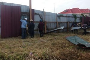 Workers from GWI removing the outer layer of zinc sheets from Peter Ramsaroop’s fence. (GWI photo)
