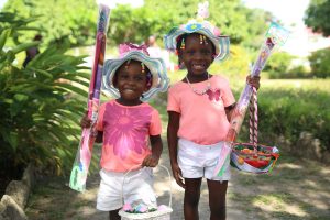 These two could barely hide their excitement as they  went to the Hat Show at the Promenade Gardens  on Saturday equipped not only to showcase their Easter hats but also to do some kite flying. (Photo by Keno George) 