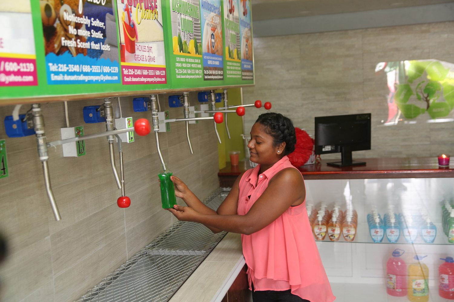 A demonstration of how to use the dispensers to refill an empty detergent bottle at the Tidy-Up Detergent Refill Centre, which was officially opened in the Diamond Housing Scheme on Saturday. 