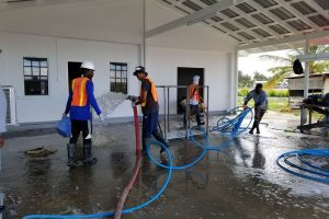 Workers of the Ministry of Public Infrastructure’s core group washing the yard of the Leonora Cottage Hospital.