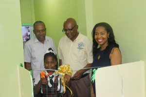 Schoolgirl, Euphoria Caesar cuts the ribbon to officially declare the facility open. Cheering her on from left are: Pastor Elsworth Williams of the Heavenly Light Church; NDMA Director, Phillip Walcott and Councillor Carolyn Caesar-Murray. (DPI photo)