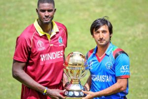 West Indies captain Jason Holder (left) shares a laugh with Afghanistan skipper Asghar Stankzai while posing with the tournament trophy, ahead of today’s final. (Photo courtesy ICC Media)
