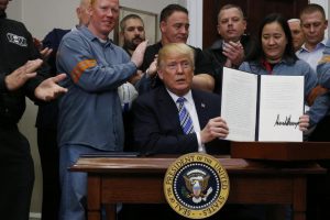 U.S. President Donald Trump holds up a proclamation during a White House ceremony to establish tariffs on imports of steel and aluminum (Reuters photo)