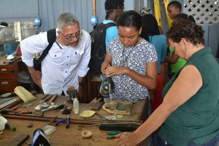 Business Minister Dominic Gaskin (left) observing a student crafting a jewellery piece (DPI photo)