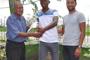 Racing Secretary of the Guyana Cycling Federation Hassan Mohammed, left, hands over the donations to Walter Grant-Stuart.