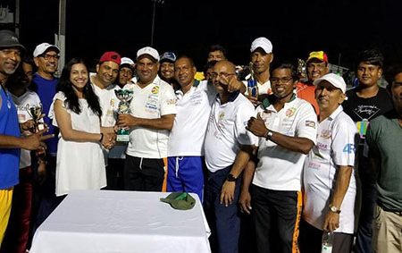 Bibi Sangster of the USA hands over the winning trophy to captain Ricky Deonarain in the presence of the smiling birthday boy Ramesh Sunich and others
