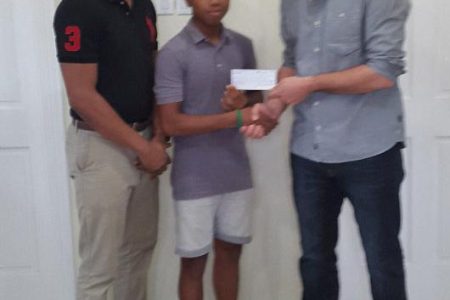 National junior table tennis star Terrence Rausch receives the sponsorship cheque from Kevin Pipegrass. At left is GTTA president Godfrey Munroe.
