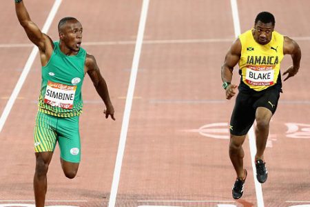 South Africa’s Akani Simbine raises his hand in triumph after beating pre race favourite Yohan Blake, right, in the men’s 100m final at the Commonwealth Games yesterday.
