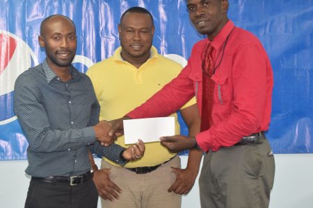 Pepsi Brand Manager Larry Wills (left) hands over the sponsorship cheque to Petra representative Mark Alleyne (right) in the presence of Petra Co-Director Troy Mendonca