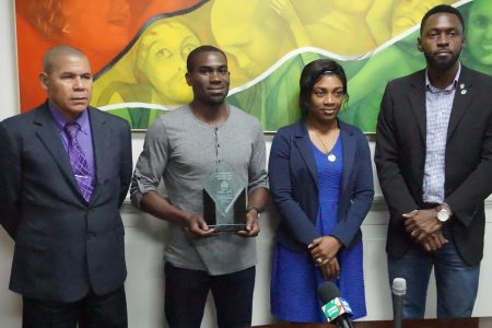 Troy Doris (second from left) poses with his plaque of achievement as Minister George Norton, Melissa Tucker, Permanent Secretary, Department of Social Cohesion, Culture, Youth and Sport, and Director of Sport, Christopher Jones look on.

