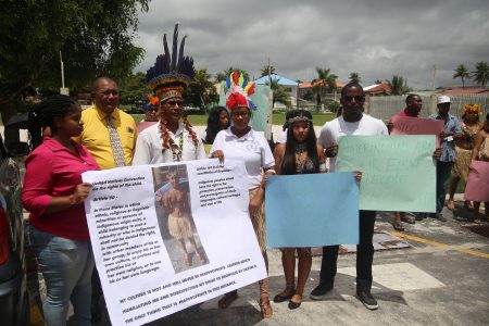 The boy’s mother, Karen Small (left) holds a placard showing her son in his traditional wear, and quoting articles from the Convention on the Rights of the Child and Guyana’s Constitution, which speak to the protection of indigenous rights. Chairman of the National Toshaos Council, Joel Fredericks (third, from left), condemned the actions of the school, and called for the government to speak up on the matter, as he noted that events such as the one last week do nothing to promote social cohesion. (Terrence Thompson photo)