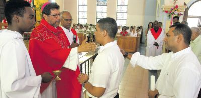 Archbishop Jason Gordon prays for Michael Thorne, of Presentation College, San Fernando, during the Holy Sacrament of Confirmation at the Our Lady of Perpetual Help RC Church, San Fernando, yesterday. Also in picture is Thorne’s sponsor Angostura chairman Dr Rolph Balgobin.