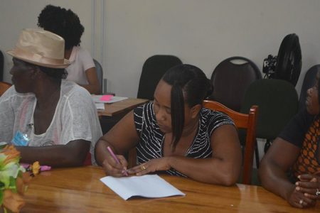 One of the young female contractors signs the document (Region Four photo)