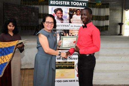 First Lady Sandra Granger handing over a certificate to the lone male Keswick Barry (Department of Public Information photo)