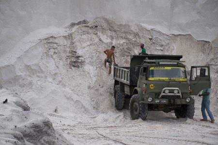 Men loading sand into a truck while in the face of the sand wall (DPI photo)