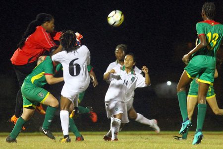 Suriname goalkeeper Nathalie Benjamine (red) punches the ball clear during a cornerkick against Guyana in their group-E clash in the CONCACAF Women’s Qualifiers at the National Track and Field Center, Leonora last evening. (Orlando Charles photo)

