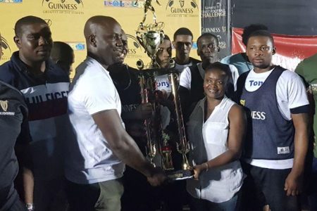 Junior Innis, coach of Silver Bullets receives the championship trophy from Linden Branch Manager Shondel Easton, following his side’s 3-1 victory in the Guinness 'Greatest of the Streets' Linden championship. Also prominent in the picture are Outdoor Events Manager Mortimer Stewart (left) and Guinness Brand Manager Lee Baptiste (right)
