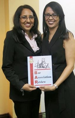 Bar Council Members Jamela Ali (left) and Pauline Chase holding a copy of the new Bar Association Review (Bar Association photo)