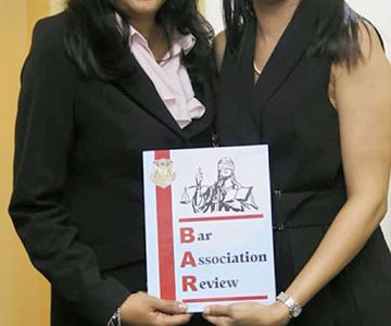 Bar Council Members Jamela Ali (left) and Pauline Chase holding a copy of the new Bar Association Review (Bar Association photo)