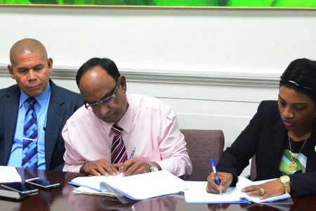 Guyana Amazon Warriors Team Operations Manager, Omar Khan (centre) and Permanent Secretary of the Ministry of Social Cohesion, Melissa Tucker sign the agreement in the presence of Minister of Social Cohesion, Dr George Norton (Orlando Charles photo)
