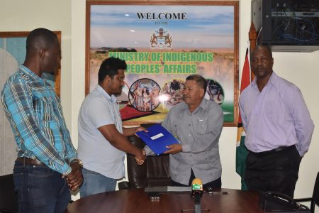Minister of Indigenous Peoples’ Affairs Sydney Allicock (second from right) receiving the contract from a representative of contractor Satar Mohamed and Hardware Supplies in the presence of Permanent Secretary Alfred King (at right) and Engineer Trilloyd Allen.