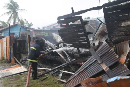 A firefighter hosing the charred remains of the house. (Terrence Thompson photo)