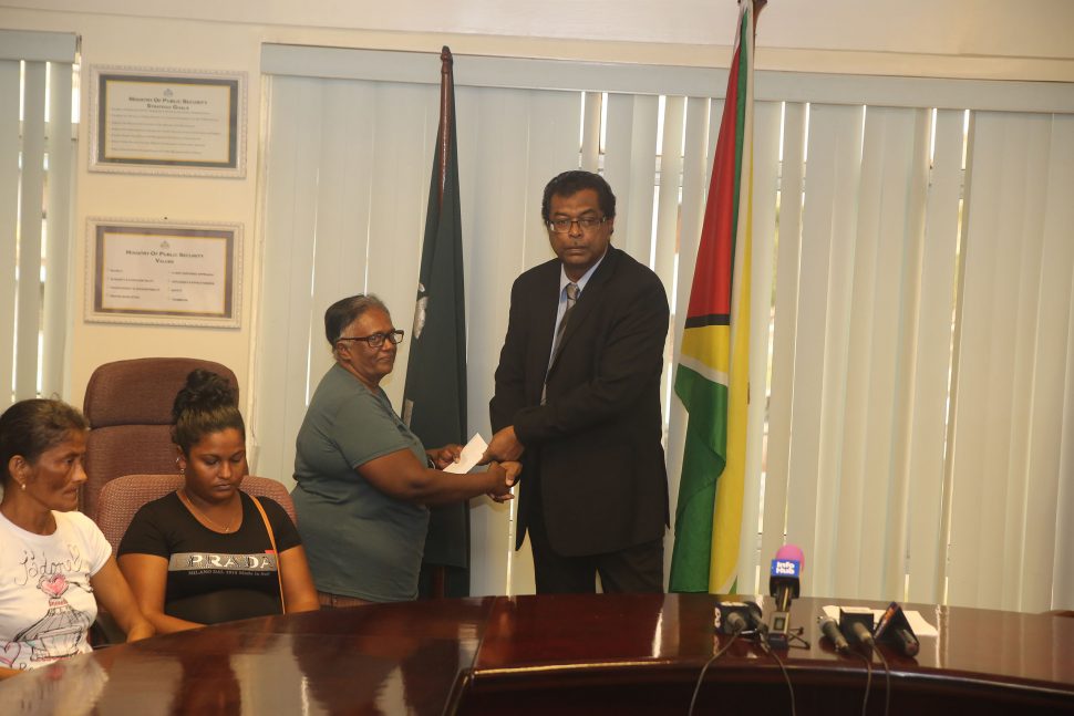 A relative of pirate attack Sunil Ramotar receiving the cheque from Minister of Public Security Khemraj Ramjattan (at right) yesterday morning. (Terrence Thompson photo)