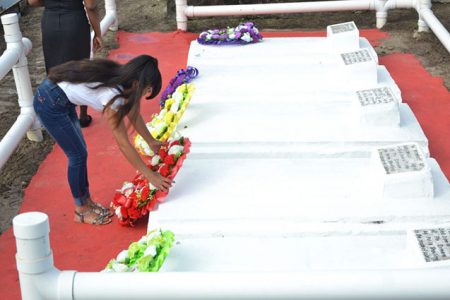 A young descendant of one of the five Enmore Martyrs lays a wreath at his gravesite at Le Repentir Cemetery, Georgetown, during a ceremony to mark the 70th anniversary of the Plantation Enmore strike where they lost their lives. (Department of Public Information photo) 