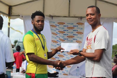 Winston Missigher receives his prize from Athletics Association of Guyana President Aubrey Hutson.