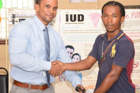 Dennis Gomes (right), youngest father receives a hamper from the Coordinator of the Men’s Health Unit of the Ministry of Public Health, Dr. Dennis Bassier. (DPI photo)
