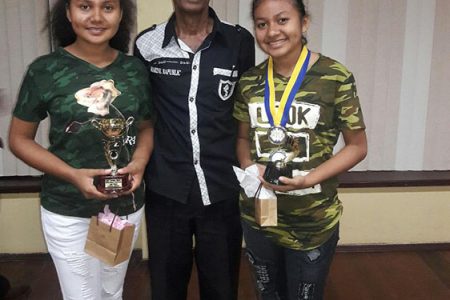 The Johnson sisters, Nellisha (left) and Waveney (right) flank their chess coach Rai Sharma at the presentation of prizes reception hosted by the Guyana Chess Federation at the National Racquet Centre recently. Nellisha and Waveney, students of Christ Church Secondary School, placed third and fourth respectively in the women’s national championship. 