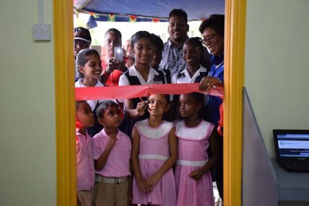 Minister of Public Telecommunications, Catherine Hughes (right) smiles as a pupil of Cumberland Primary cuts the ribbon. (DPI photo) 