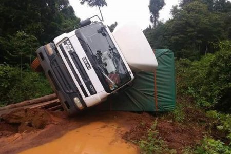 Dangers along Linden to Lethem trail: Trucks continue to topple as the condition of the Linden-Lethem road deteriorates daily. Stabroek News understands that on Monday, this truck, which was transporting goods at the time, toppled after trying to manoeuvre in an area known as 33 Bridge. While no harm came to the driver, the bridge has suffered some damage. Road users continue to criticize the state of the Linden to Lethem trail, saying that the situation has become “unbearable.”  (Photo by Suzie Narine) 