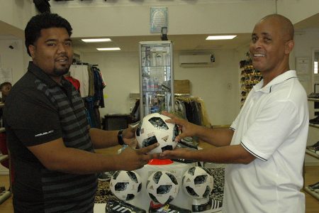 Managing Director of Chetsons Inshaan Ramkellawan (left) hands over one of the balls to Three Peat Promotions Rawle Welch last Thursday, at the entity’s Wellington Street location.