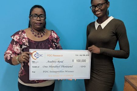 PDC-Research Sweepstakes winner Audrey Reid (left) receiving a cheque from PDC Founder Anije Lambert.